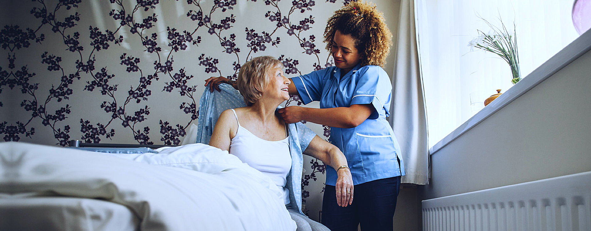 caregiver assisting elder woman in dressing
